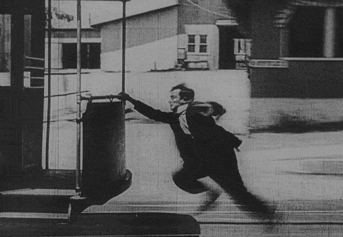 Image animée de charlie chaplin qui court derrière un tramway